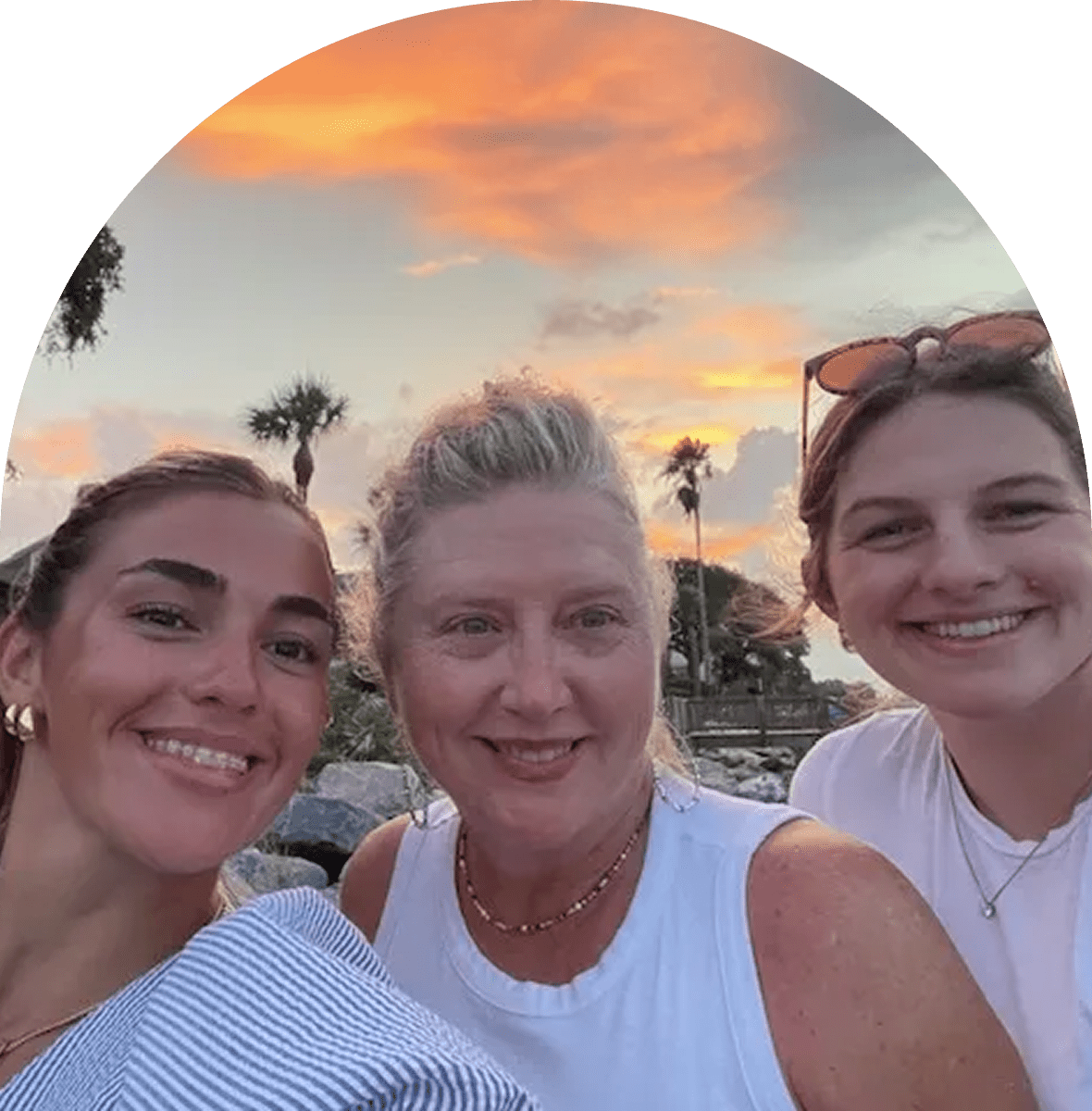 Three women smiling at sunset